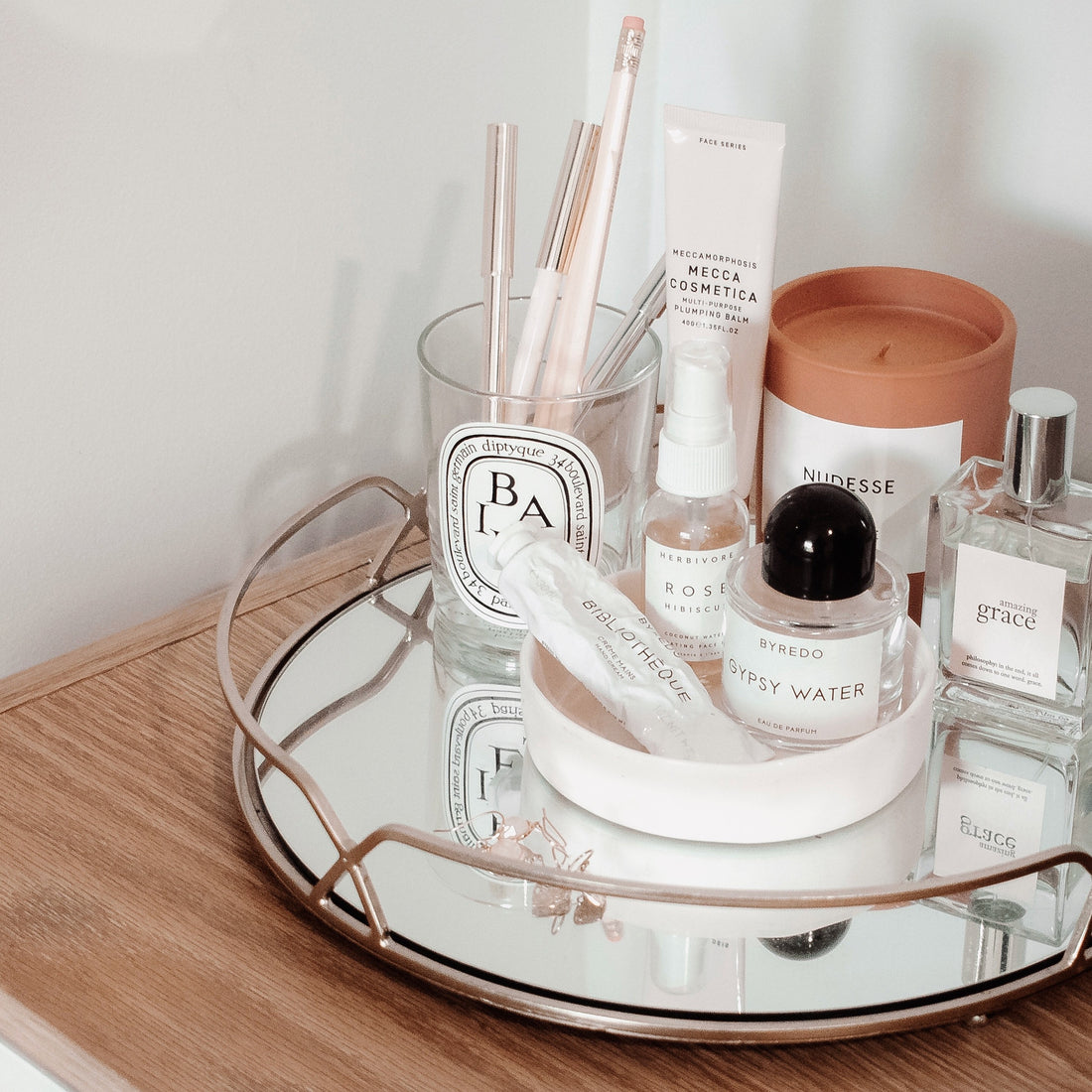 vanity with mirror plate highlighting candle, gypsy perfume, few eyeliners and other beauty products
